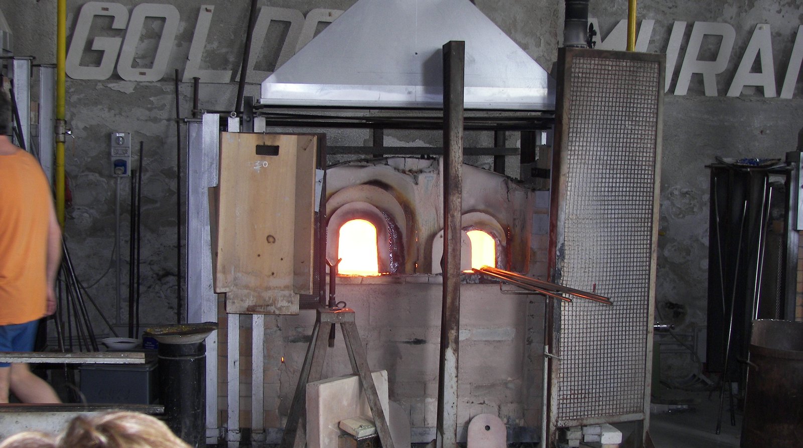 A glassmaker working at a furnace inside a Murano workshop.