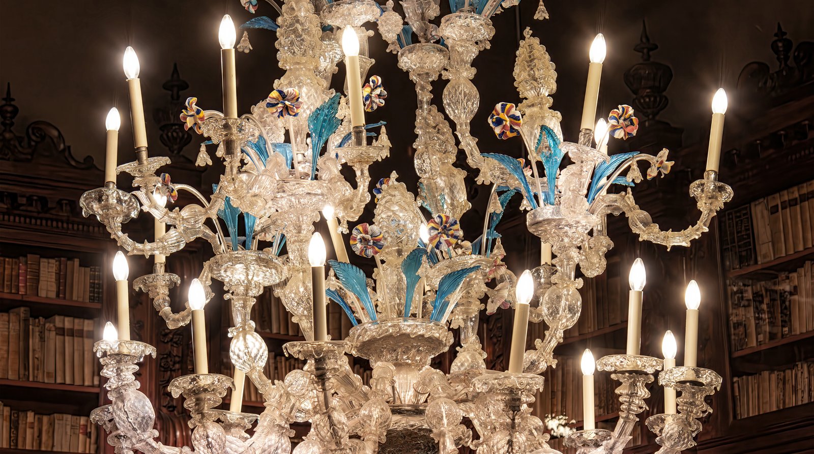 An ornate Murano glass chandelier hanging inside a historic Venetian interior.