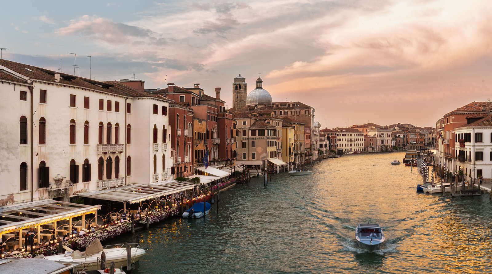 The Grand Canal at sunset, its buildings lit in warm evening light.