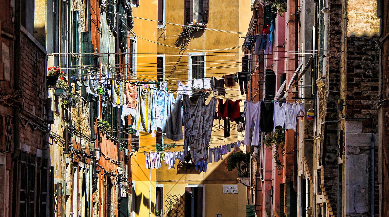 A narrow Venetian calle strung with laundry lines between the buildings.