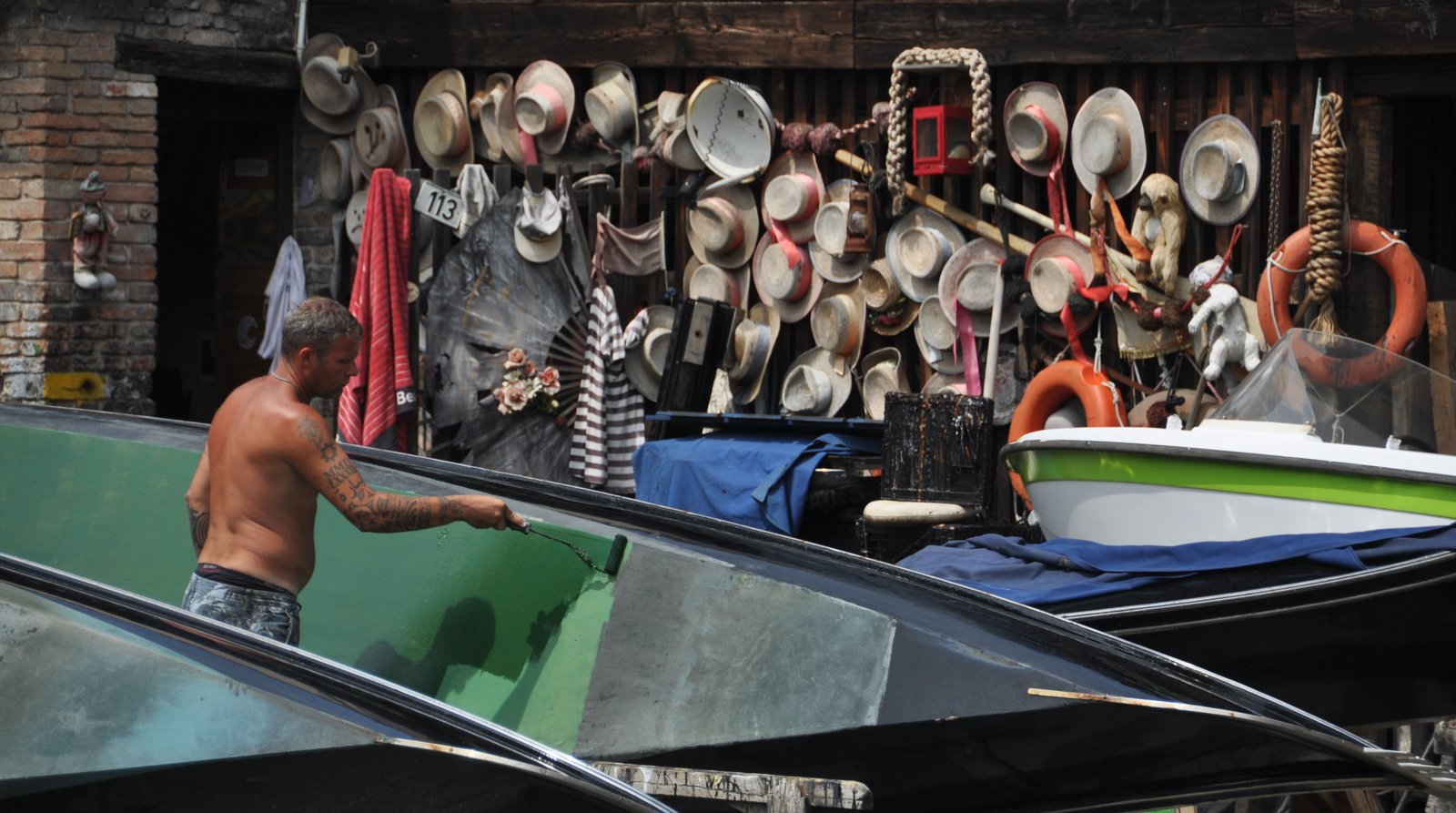 A craftsman repairing a wooden gondola hull inside a Venetian boatyard.