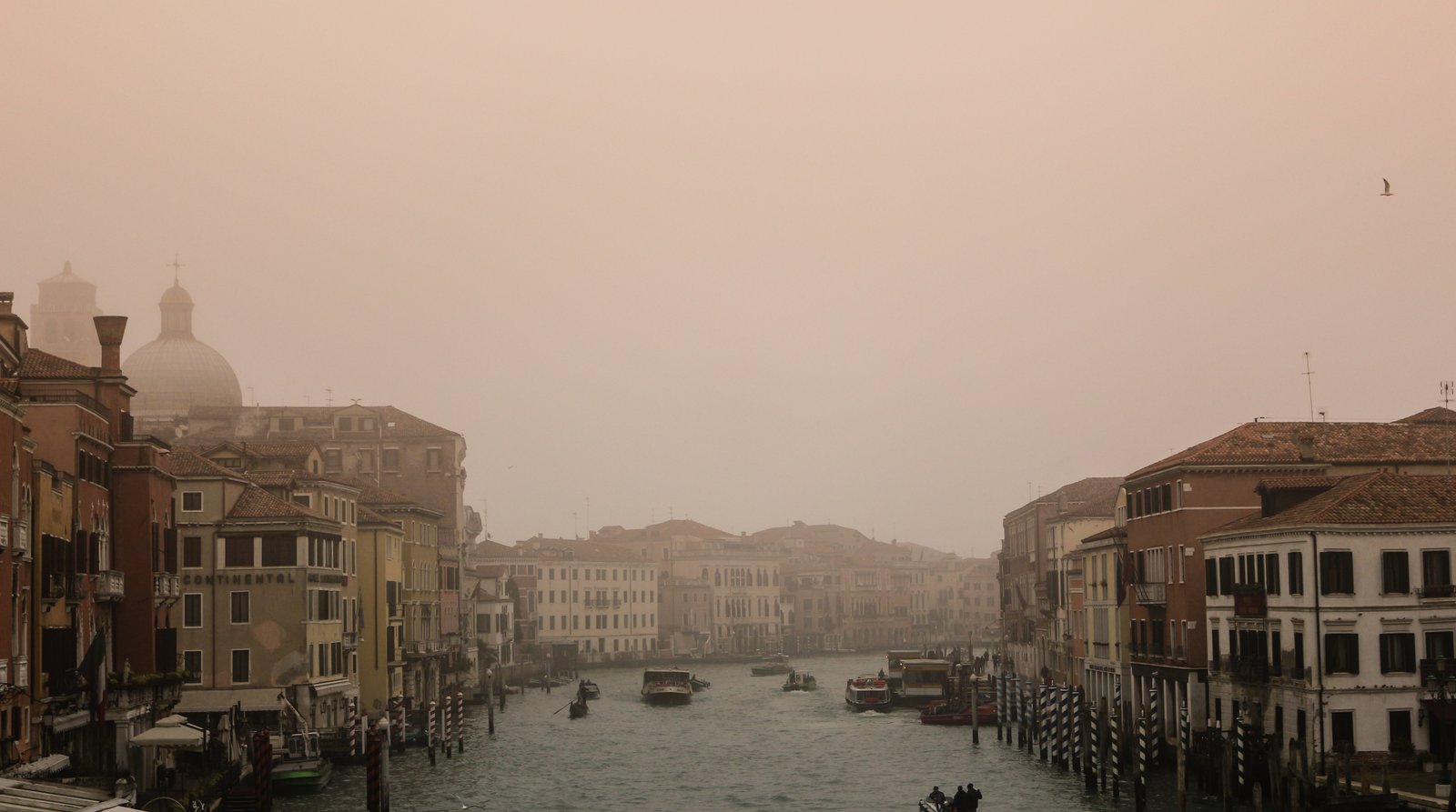 A misty, quiet Venice canal in winter with almost no one about.