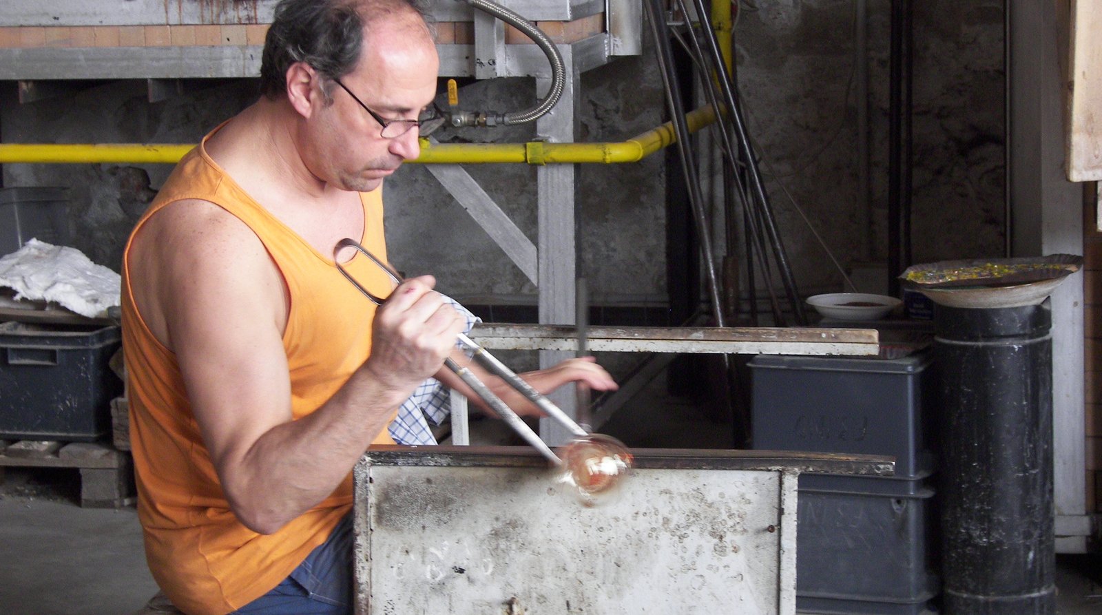 A glassblower shaping molten glass at a Murano furnace.